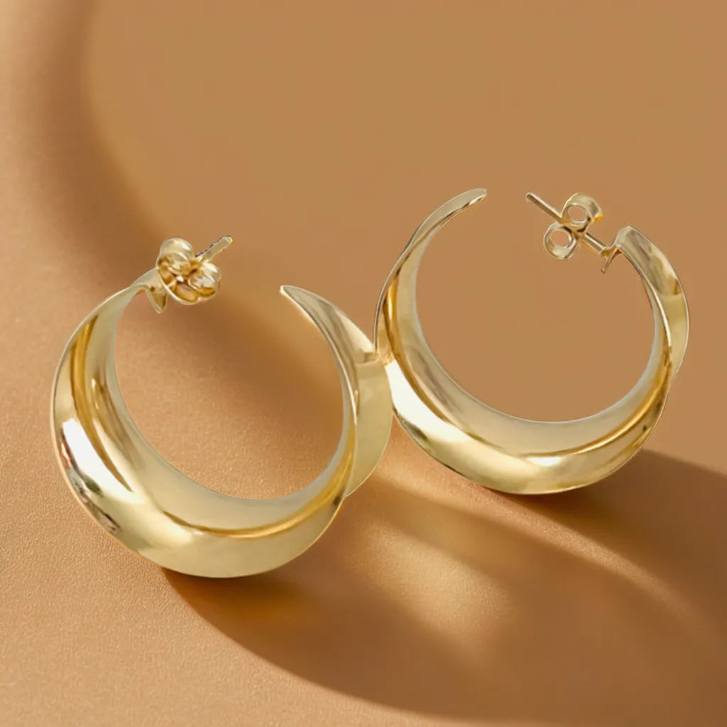 Gold earrings for women with curved hoop design on neutral background
Close-up of Parisian-style gold hoop earrings (33x15mm)
Model styling lightweight gold earrings for woman with elegant outfit