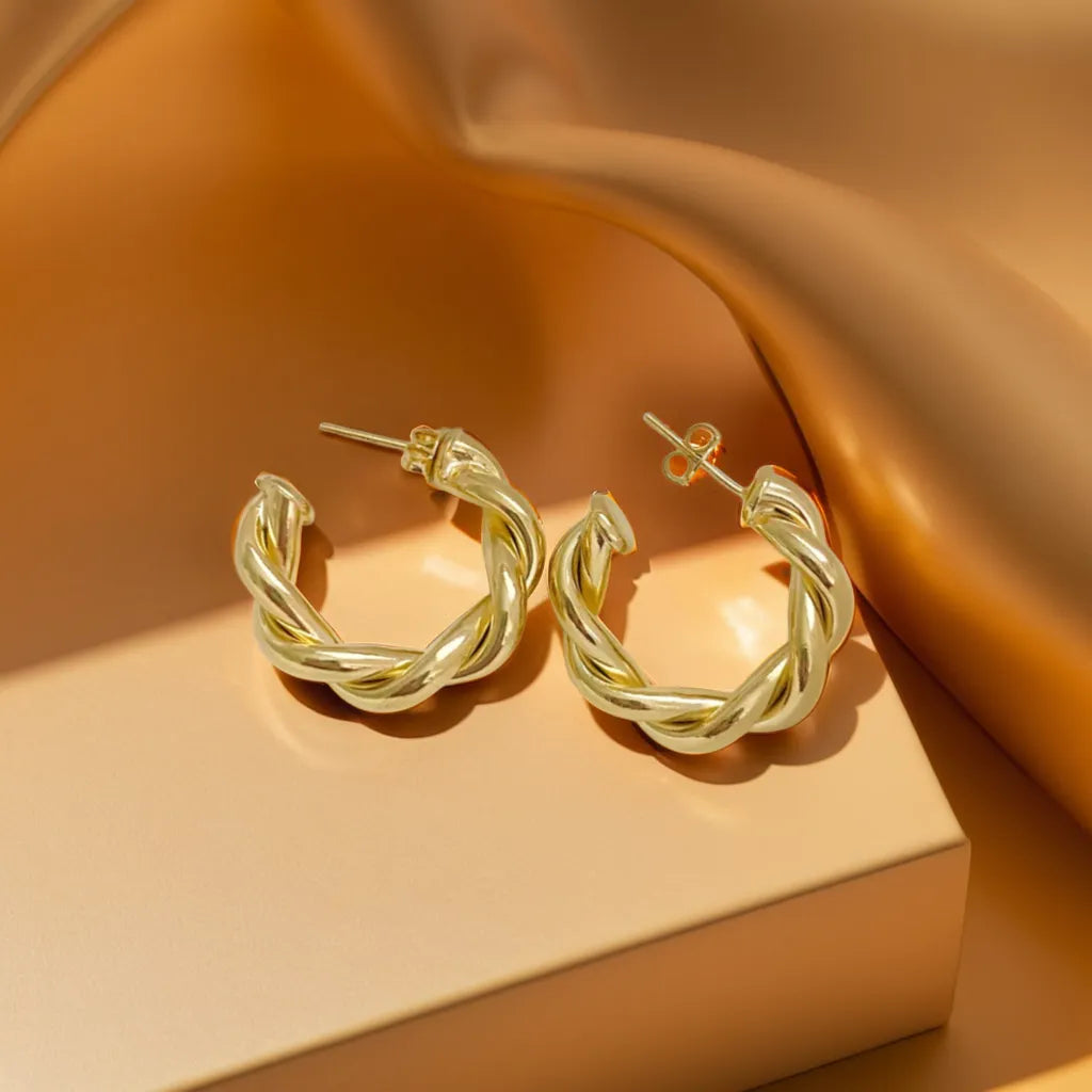 Gold earrings for women with twisted hoop design flat lay
Close-up of 18K gold hoop earrings showing polished texture
Model wearing women gold earrings styled with minimalist outfit