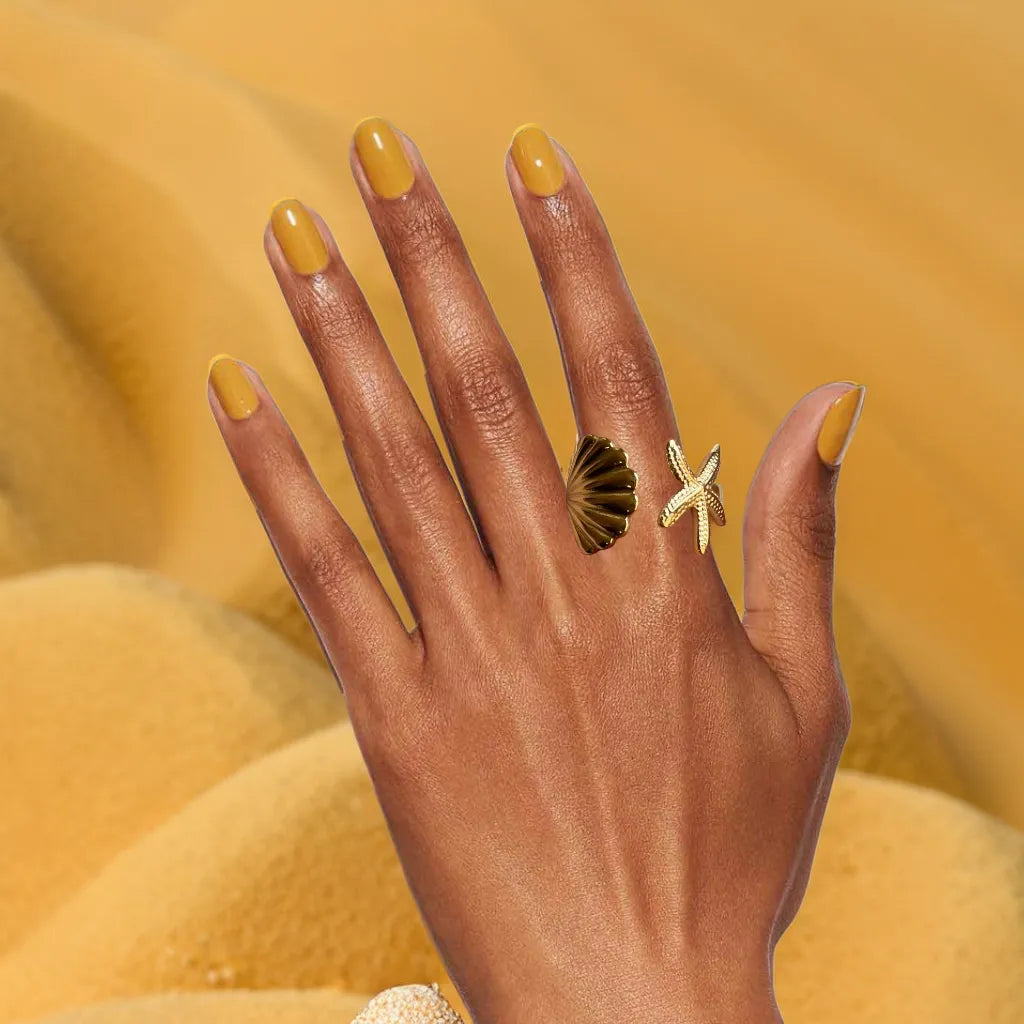 Women gold ring with starfish and shell design – front view
Gold plated ring for woman – side profile of coastal motif
Anneau Trésor Marin – adjustable gold ring with beach-inspired details
Gold ring for woman – ocean-themed jewelry on hand m