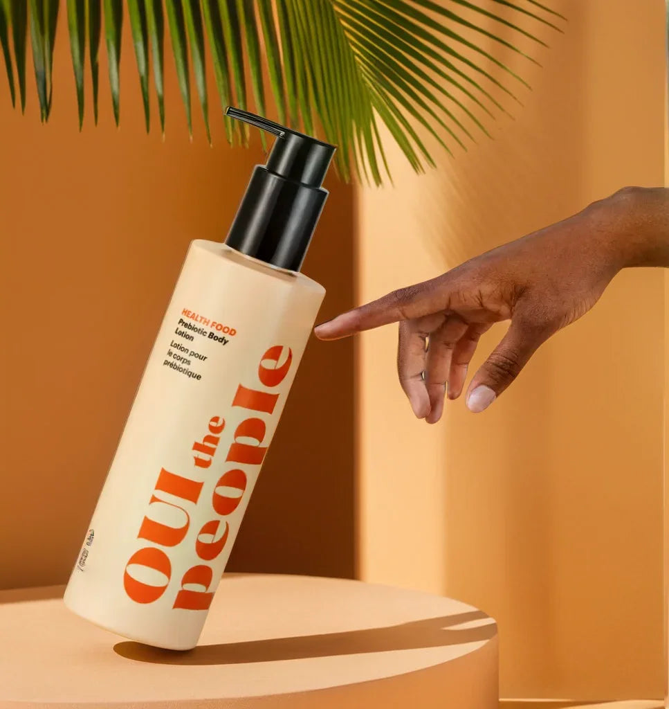 Out the People body lotion bottle with a hand pointing to it against an orange background