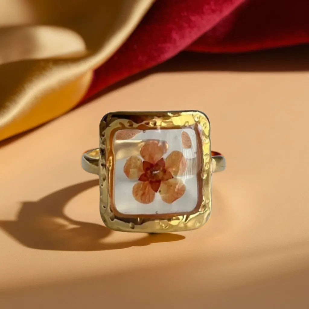 Woman Gold Ring with Pressed Flower | Bague Fleur Rose
This woman gold ring features a real pressed pink flower in a gold-plated setting. Adjustable, romantic, and perfect for everyday elegance.
Gold ring with pressed pink flower – top view
Botanical woman gold ring – romantic floral design
Bague Fleur Rose Éternelle – square gold ring with flower
Gold plated ring for women – pink flower close-up