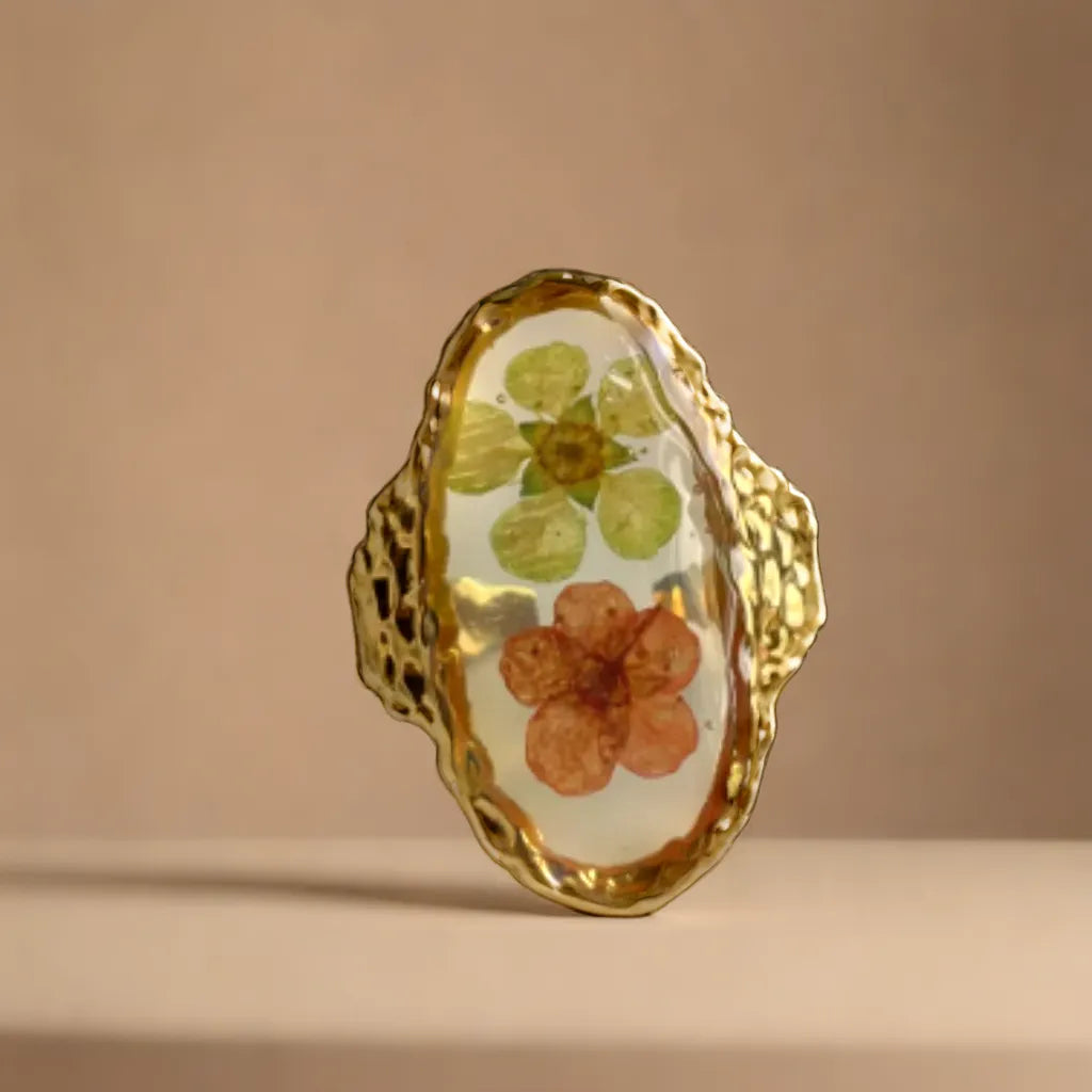 Woman Gold Ring with Pressed Flowers – Botanical Elegance
Close-up of gold ring with pink and green pressed flowers – woman gold ring
Side angle of floral gold plated ring – botanical jewelry for women
Adjustable gold ring with real flowers – gold plated ring romantic style
Ring styled on model hand – gold ring for woman with French elegance