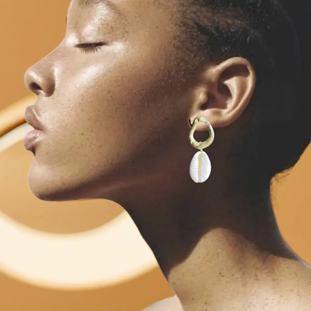 Women Gold Earrings – Cowrie Shell Hoops | Créoles Trésor de l’Océan
Embrace seaside charm with these women gold earrings featuring real cowrie shells and 18K gold plating. Lightweight, elegant, and made to shine.
Women gold earrings with cowrie shell – close-up on white background
Cowrie shell hoop earrings gold plated – coastal style jewelry
Créoles Trésor de l’Océan – gold shell earrings in natural light
Boho chic gold earrings for woman – beach-inspired design