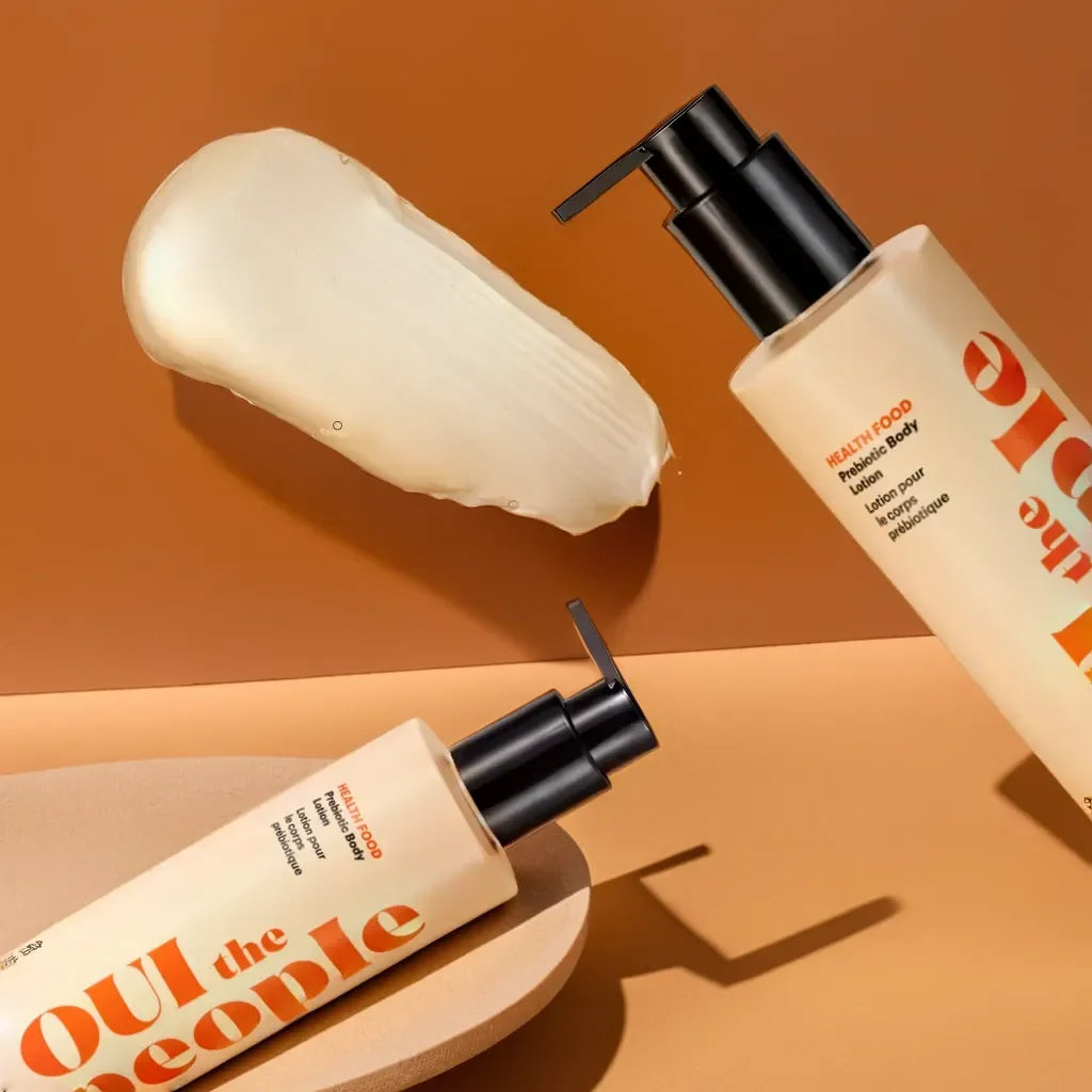 Two bottles of 'Out of the People' skincare product on a warm brown background