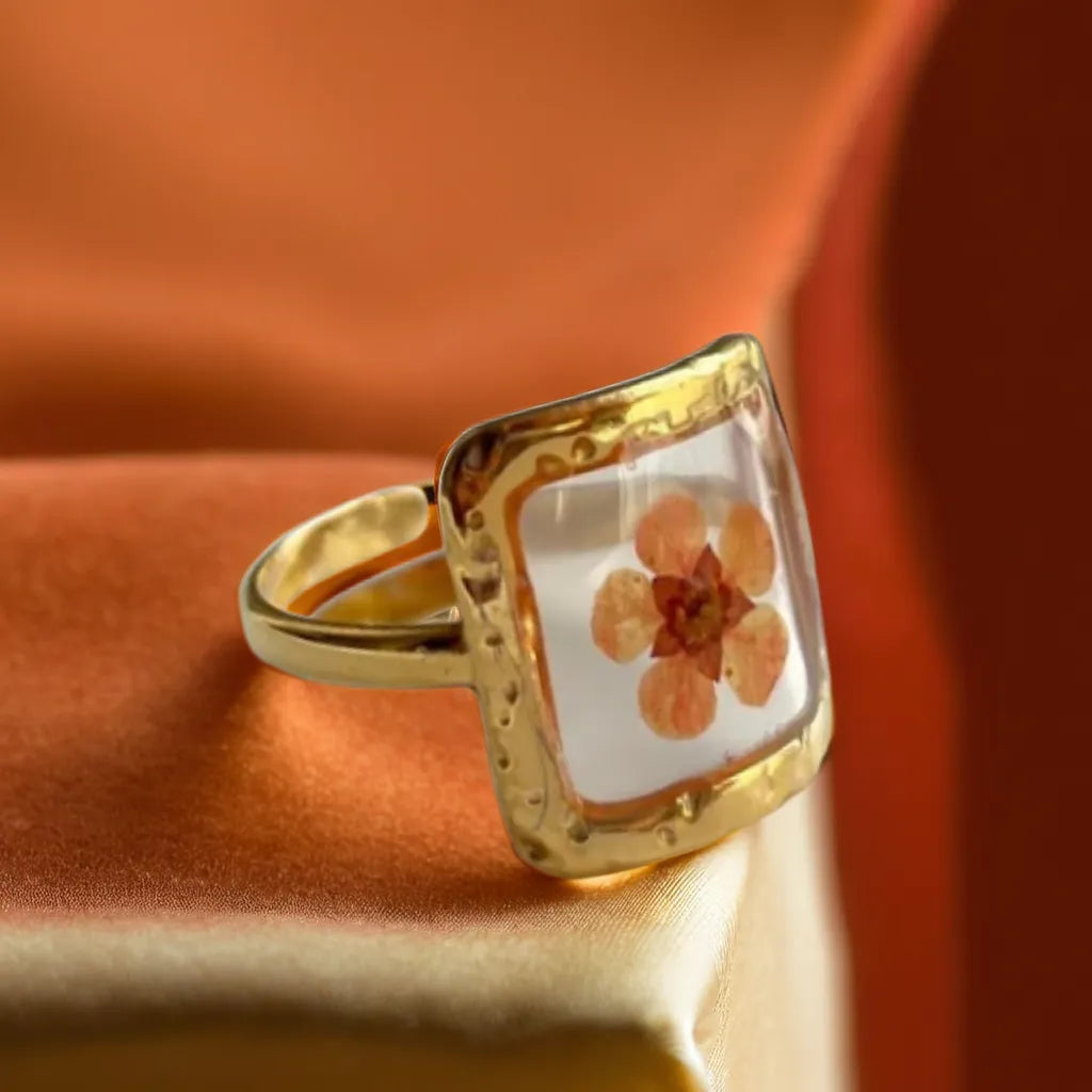 Woman Gold Ring with Pressed Flower | Bague Fleur Rose
This woman gold ring features a real pressed pink flower in a gold-plated setting. Adjustable, romantic, and perfect for everyday elegance.
Gold ring with pressed pink flower – top view
Botanical woman gold ring – romantic floral design
Bague Fleur Rose Éternelle – square gold ring with flower
Gold plated ring for women – pink flower close-up