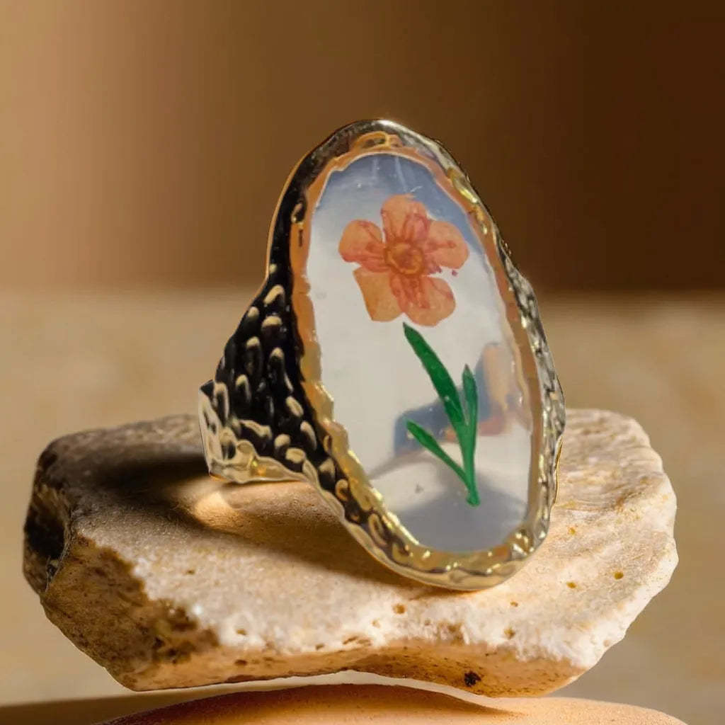 Woman gold ring with delicate pressed flower – top view
Gold plated flower ring for women – romantic floral design
Adjustable gold ring with botanical motif – side angle
Nature-inspired woman ring – styled hand shot