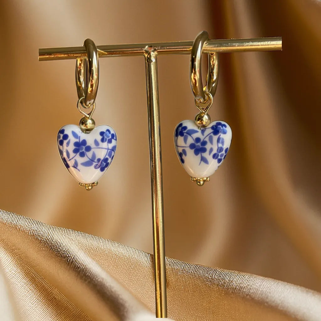 gold earrings women heart Mediterranean huggie hoops

18k gold plated heart earrings close-up

heart tile charm earrings for woman

gold huggie hoop earrings with heart pendant