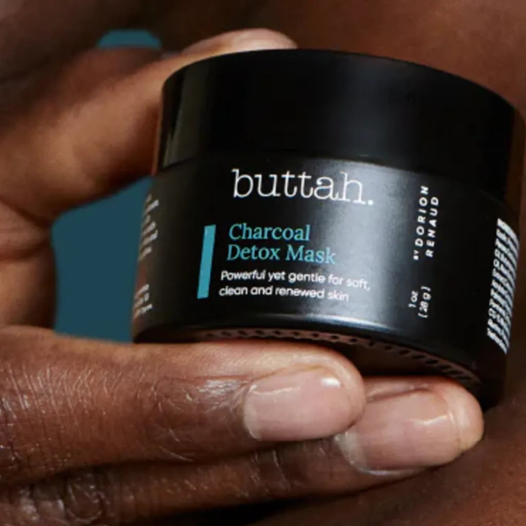 Black clay mask swatched on rich brown skin

Face with mask applied and rinsed

Product jar with charcoal and shea nuts

Skin after use—soft, smooth, radiant